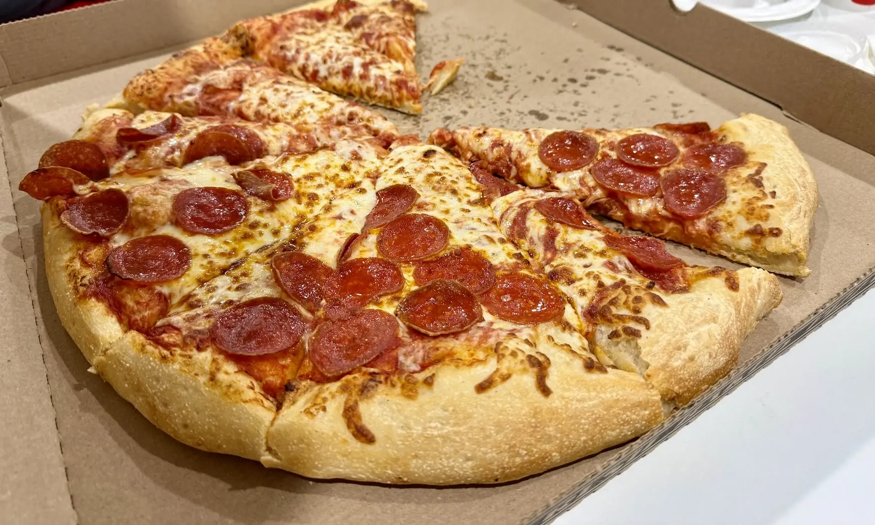 A pepperoni and cheese pizza in a cardboard box at a Costco food court