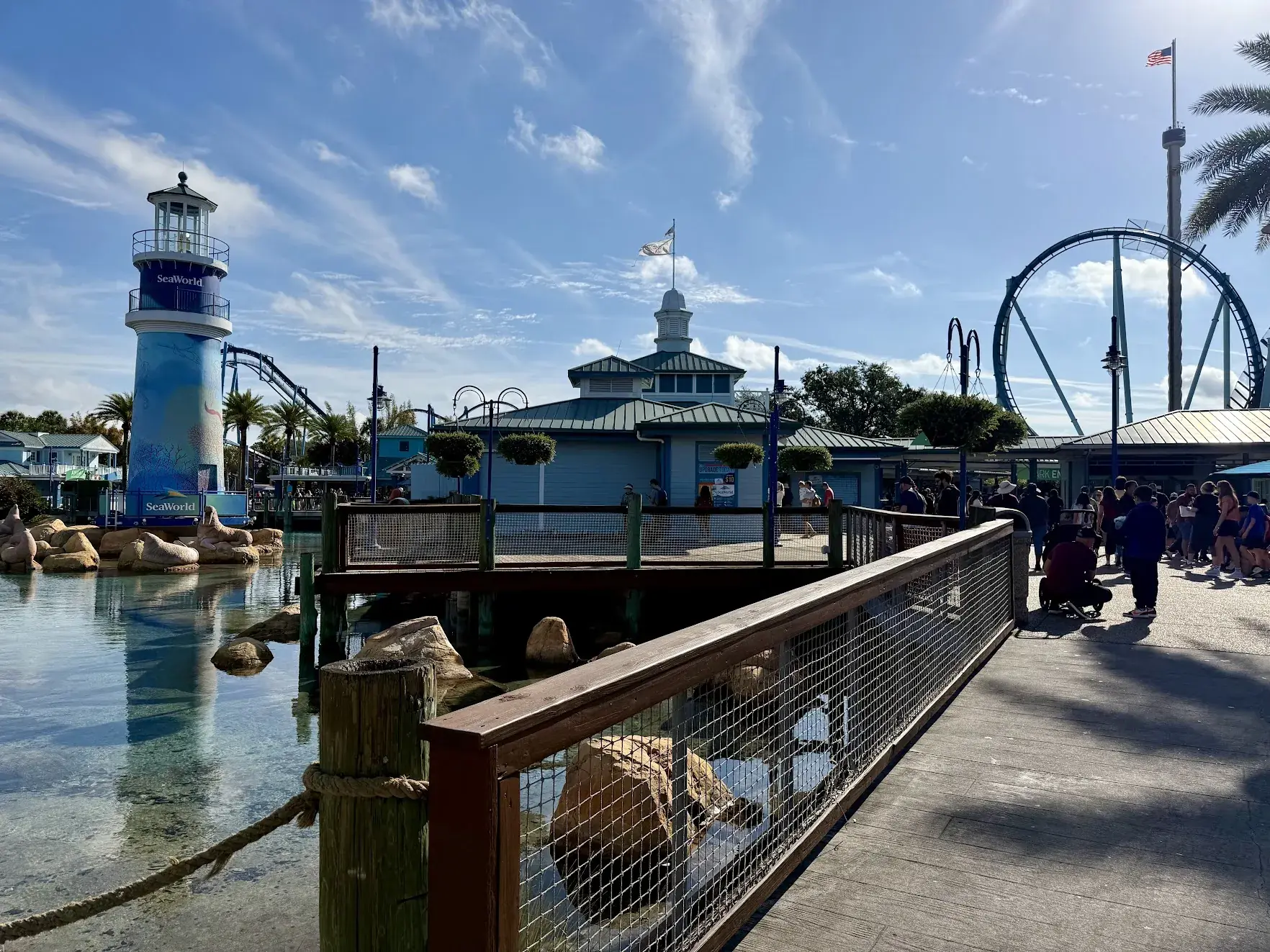 The SeaWorld Orlando lighthouse beside a lagoon, with a roller coaster loop in the background