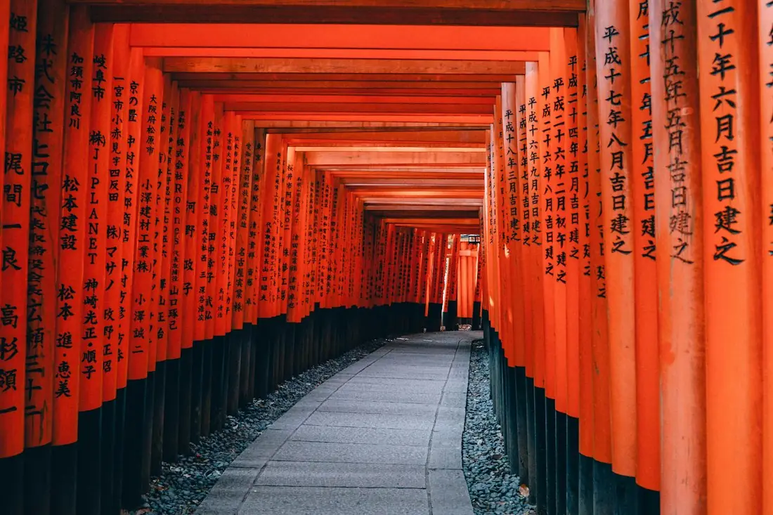 A path through rows of orange torii gates at Fushimi Inari, Kyoto