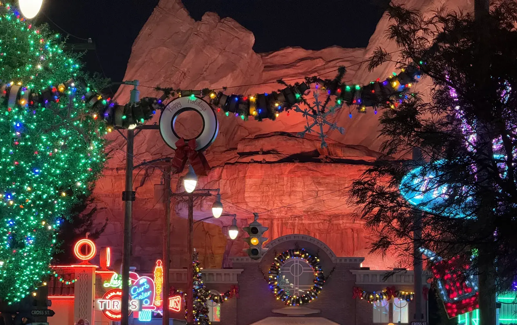 Radiator Springs in Cars Land at night, with Christmas lights, neon signs and red rock cliffs