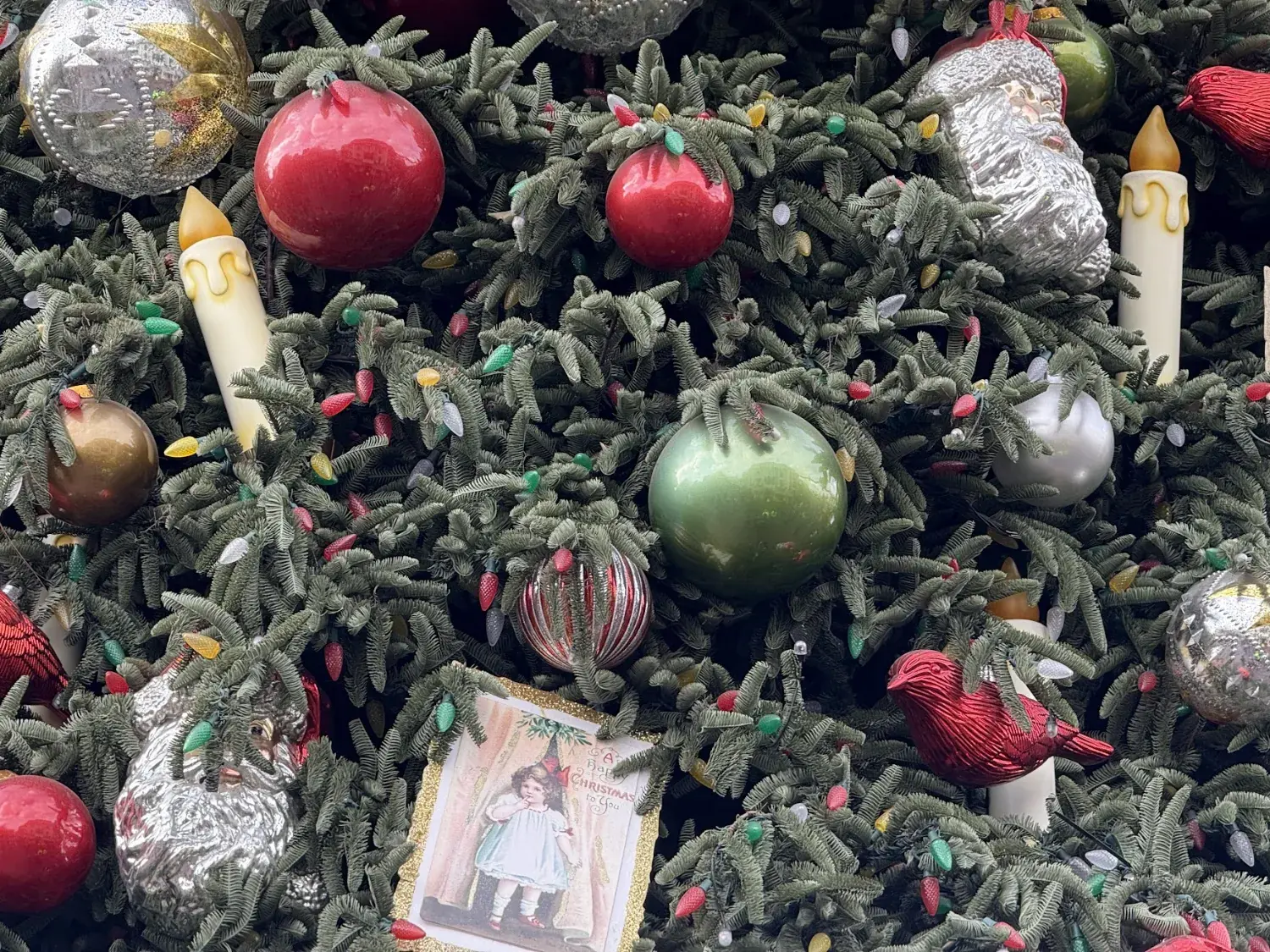 Close-up of vintage-style ornaments, candles and a cardinal on a Christmas tree