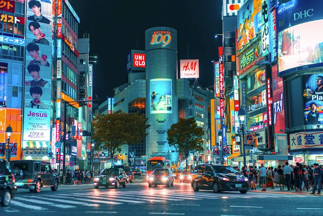Shibuya crossing in Tokyo at night with taxis and neon signs